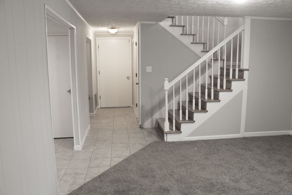 Downstairs hall way and stairs real estate photo.